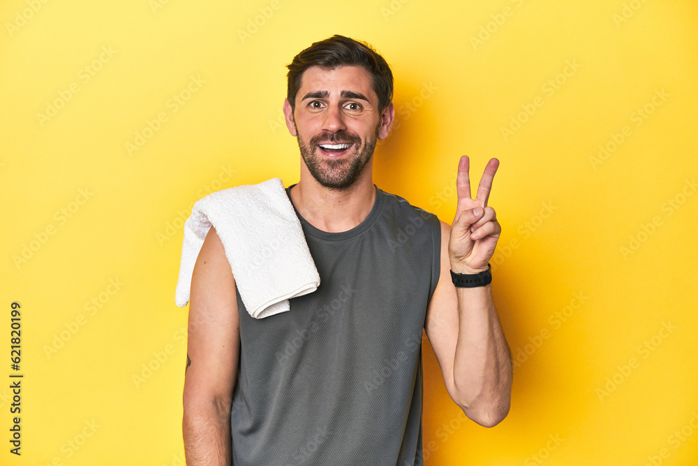 Sporty Caucasian man with towel, studio shot on yellow Sporty Caucasian man with towel, studio shot on yellowshowing number two with fingers. Sporty Caucasian man with towel, studio shot on yellow Sporty Caucasian man with towel, studio shot on yellowshowing number two with fingers.