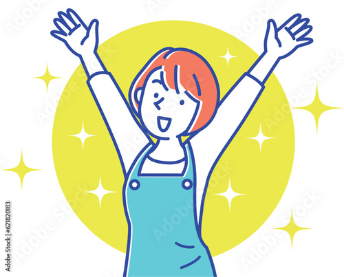 笑顔でバンザイするエプロン姿の若い女性