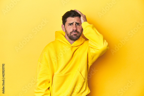 Man in yellow hoodie, monochrome studio backdrop being shocked, she has remembered important meeting.