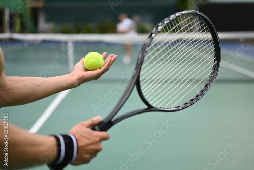 Tennis player serving tennis ball during a match on open court. Sport, fitness, training and active life concept