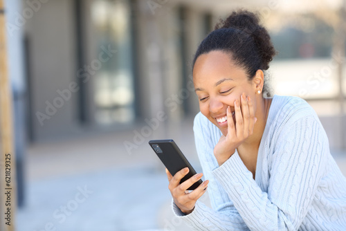 Happy black woman laughing using phone