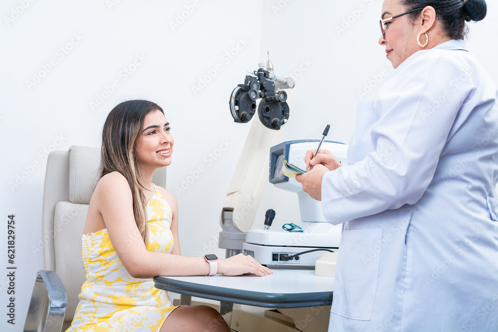 Optometrist with female patient taking notes in office. Female patient having consultation with optometrist in office Optometrist with female patient taking notes in office. Female patient having consultation with optometrist in office
