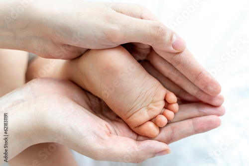 The baby's feet are in the hands of the mother.