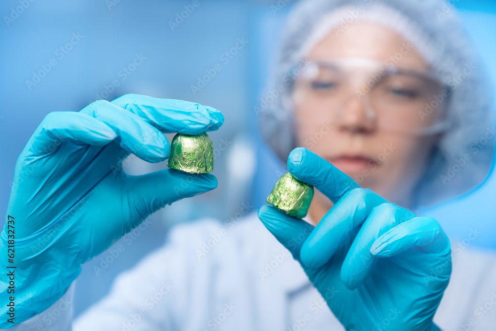 Food industry, candy factory, worker chemist tests chocolate products in laboratory, blue background