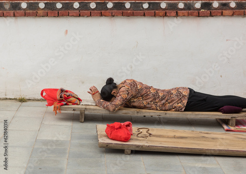 Tibetan pilgrim woman praying and prostrating in Hezuo monastery, Gansu province, Hezuo, China photo