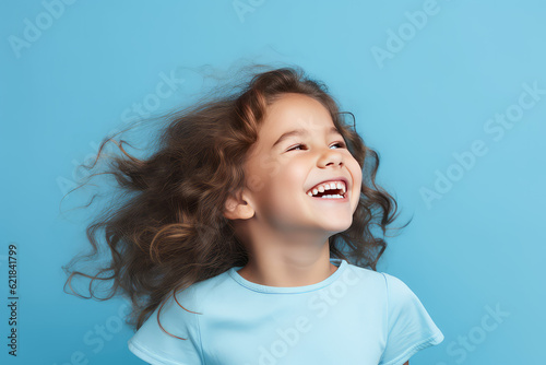 Cute junior girl laughing and smiling with curly brown hair isolated on blue flat background with copy space. Happy little girl portrait. Generative AI studio photo imitation.