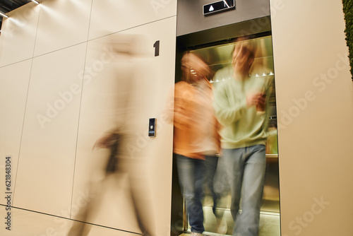 motion blur of energetic businessmen getting out elevator in contemporary coworking office, long exposure, movement, collaboration, dynamic business and productivity concept