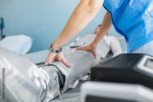 Beautician therapist preparing for pressotherapy treatment beauty salon to young man.