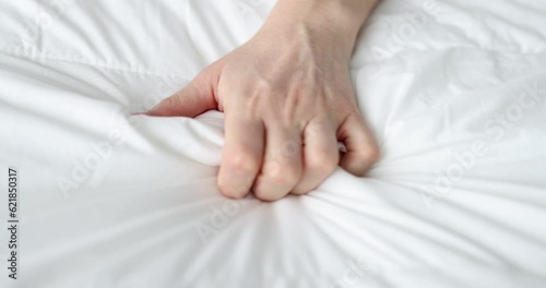 Woman hand squeezing white bed during passionate orgasm closeup 4k movie slow motion. Sexual pleasure concept photo