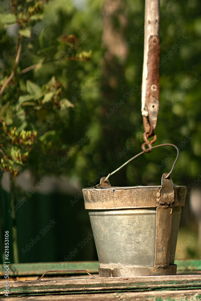 on the lid of the well there is a stainless steel bucket for a well in the countryside, for lifting water from it, the water in the wells is cold, tasty, fresh, spring, clean on the lid of the well there is a stainless steel bucket for a well in the countryside, for lifting water from it, the water in the wells is cold, tasty, fresh, spring, clean