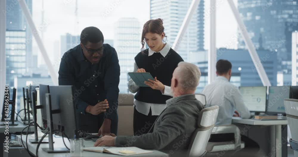 Diverse Colleagues Talking In Front Of Desktop Computer In Corporate Office With Megapolis Window View. Caucasian Male Developer Showing New Code To African CEO And His Female Assistant With Tablet. Diverse Colleagues Talking In Front Of Desktop Computer In Corporate Office With Megapolis Window View. Caucasian Male Developer Showing New Code To African CEO And His Female Assistant With Tablet.