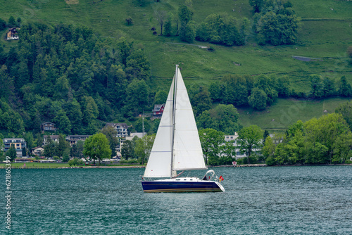 Scenic view of sailing boats on Lake Lucerne with woodland and mountains in the background on a cloudy spring day. Photo taken May 18th, 2023, Treib, Canton Uri, Switzerland.