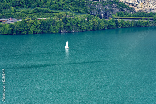 Scenic aerial view of sailing boat on lake lucern seen from hiking trail Swiss path at village Seelisberg on a cloudy spring day. Photo taken May 18th, 2023, Seelisberg, Canton Uri, Switzerland.