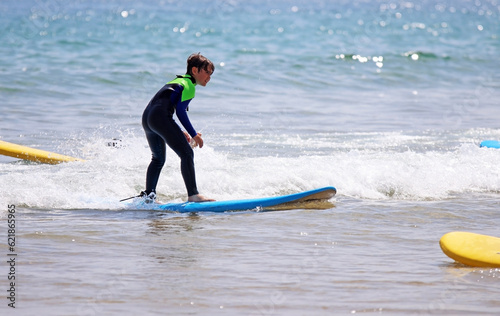 Child on a surfboard on the beach, in summer, on vacation