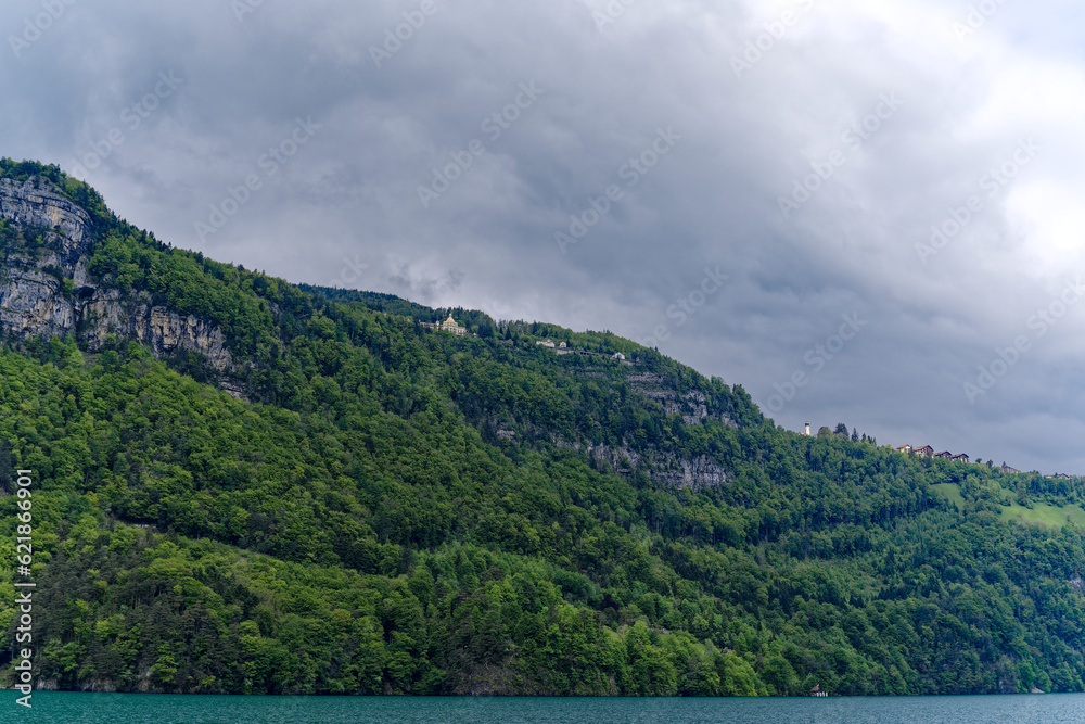Scenic landscape with rock, cliff and woodland with mountain village Seelisberg at lakeshore of Lake Uri on a cloudy spring day. Photo taken May 18th, 2023, Seelisberg, Switzerland. Scenic landscape with rock, cliff and woodland with mountain village Seelisberg at lakeshore of Lake Uri on a cloudy spring day. Photo taken May 18th, 2023, Seelisberg, Switzerland.