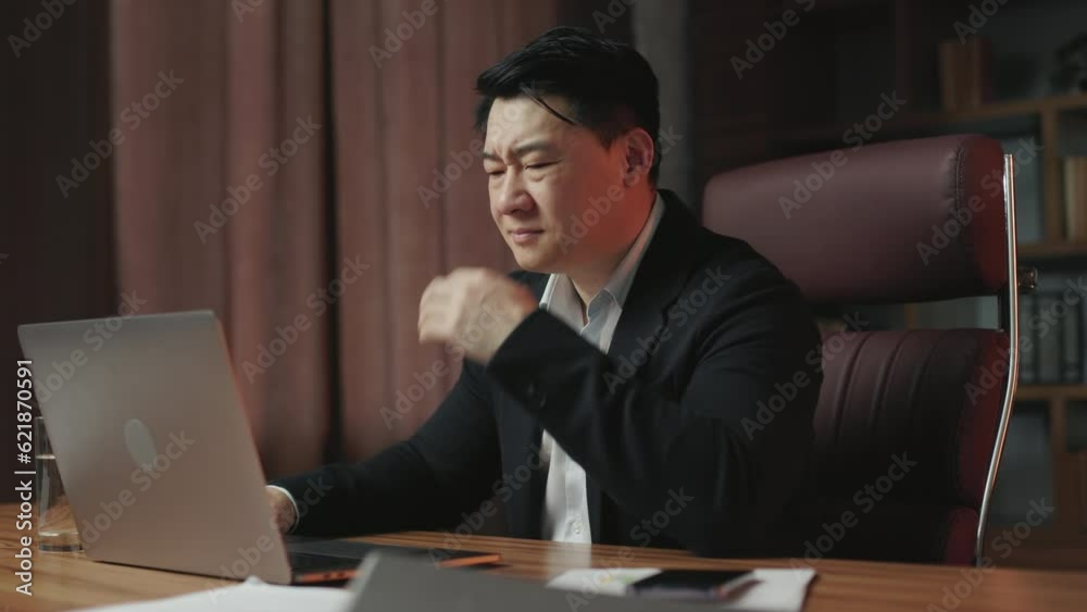 Angle view of annoyed asian man wearing formal outfit having problems with data loss at office workplace. Confused gentleman feeling stress, touching head and closing computer. Angle view of annoyed asian man wearing formal outfit having problems with data loss at office workplace. Confused gentleman feeling stress, touching head and closing computer.
