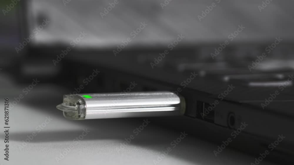 young woman inserts a flash drive into a usb port into a computer on table, close-up young woman inserts a flash drive into a usb port into a computer on table, close-up