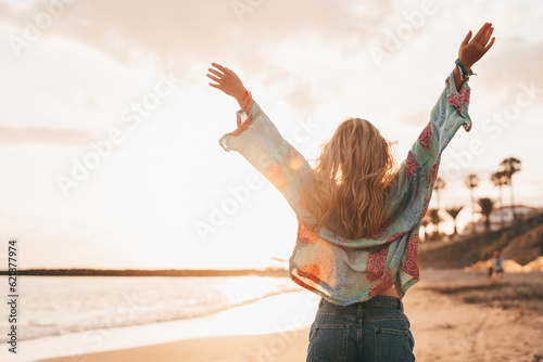 One happy beautiful woman walking on the sand of the beach enjoying and having fun at the sunset of the day. Leisure time on vacations, freedom concept. #621877974