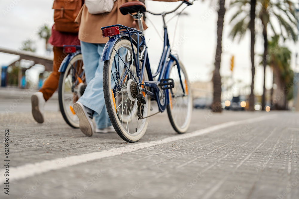 Φωτογραφία Cropped picture of two people pushing their bikes on the city street