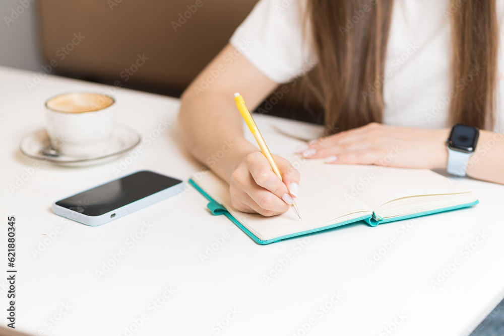 Close-up of the hands of a girl who writes in a notebook, takes notes. Freelance concept. Close-up of the hands of a girl who writes in a notebook, takes notes. Freelance concept.