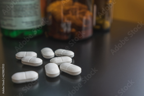 Фотография White pills on a black surface, selective focus, close up
