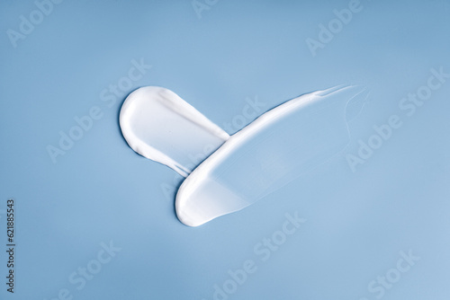 White smudges swatches smear of face or body care cream on a blue background. Pureness concept