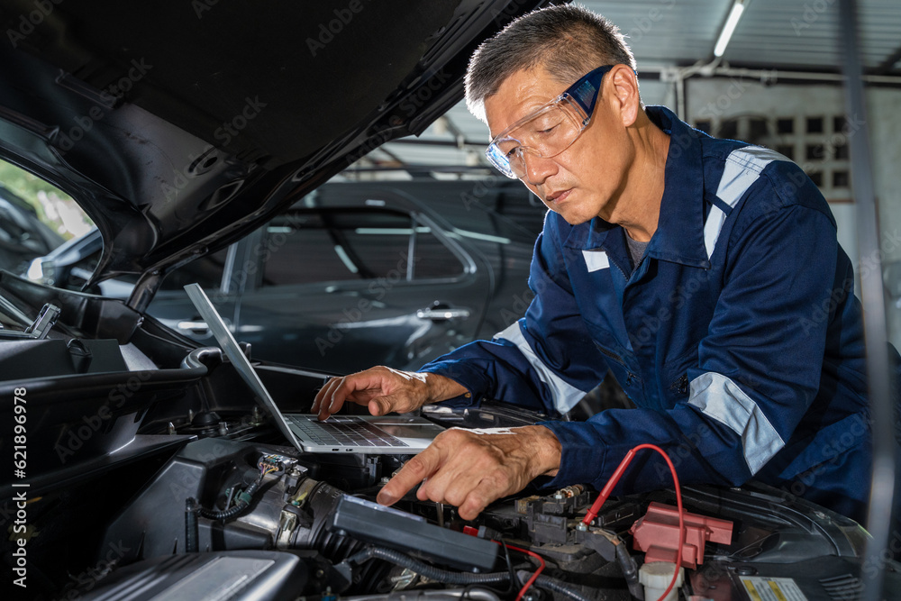 Two car mechanic standing next to a car while discussing the car repair process using computer tablet