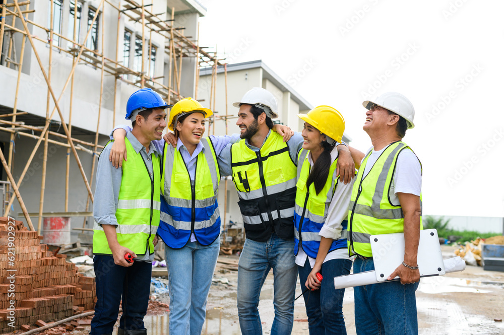 Group of happy contractors, engineers and formats in safety vests with helmets stand on the under-construction building site. teamwork concept. Group of happy contractors, engineers and formats in safety vests with helmets stand on the under-construction building site. teamwork concept.