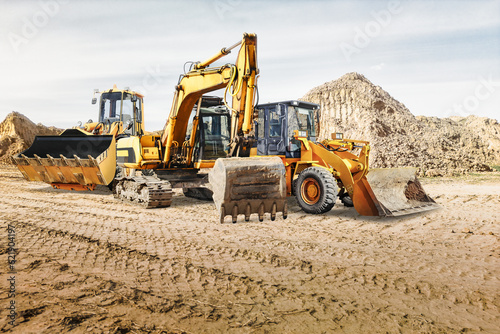 Modern construction machinery at a construction site in a quarry. Powerful modern equipment for earthworks. Rental of construction equipment. Excavator, dump truck, bulldozer, loader.