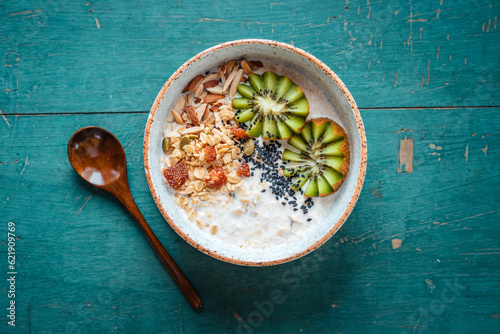 Healthy breakfast, oatmeal, kiwi and granola on green background