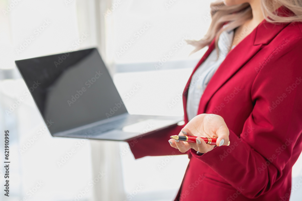 Portrait of a woman business owner showing a happy smiling face as he has successfully invested in her business using computers and financial budget documents at work.