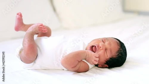 a newborn black African-American baby wakes up and crying asks to eat, a small dark-skinned baby lies on the bed in the bedroom, shuddering and crying