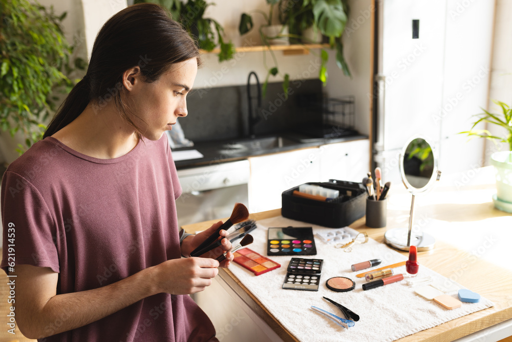 Non-binary transgender woman holding set of makeup brushes in sunny living room at home Non-binary transgender woman holding set of makeup brushes in sunny living room at home