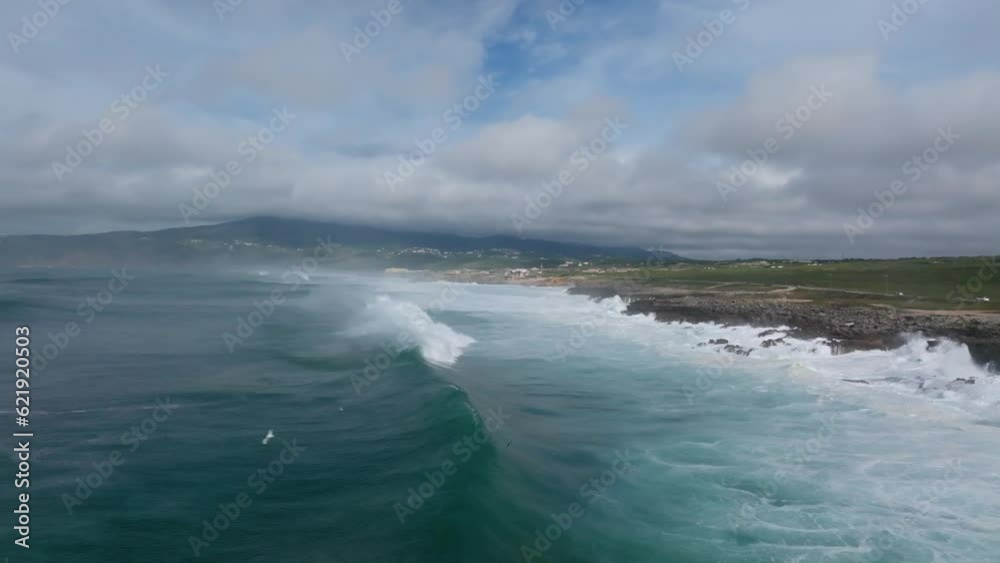 Aerial view of a huge ocean waves and a flock of seagulls flying over the water near Guincho Beach, Cascais, Portugal. Aerial view of a huge ocean waves and a flock of seagulls flying over the water near Guincho Beach, Cascais, Portugal.
