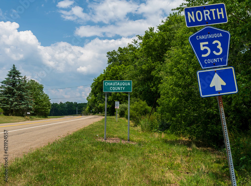 The State Route 53 North sign in front of the Chautauqua County sign in Carroll, New York, USA on a sunny summer day photo