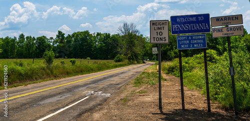 Road signs along with a Welcome to Pennsylvania sign on Akerley Road in Pine Grove Township, Pennsylvania, USA on a sunny summer day