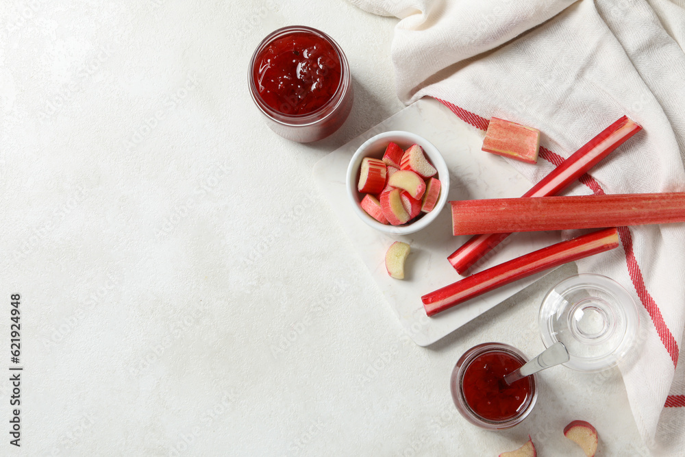 Rhubarb on white marble board, light towel and jars of jam on light background, space for text Rhubarb on white marble board, light towel and jars of jam on light background, space for text