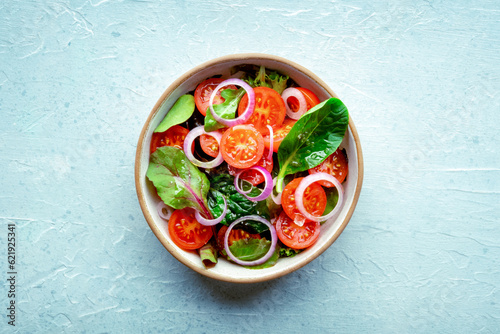 Fotografia Salad with tomato, fresh leaves, and onions, overhead flat lay shot