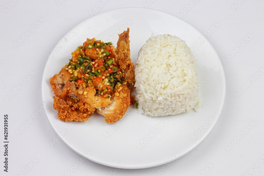 nasi ayam geprek or Spicy Geprek chicken rice culinary served on a round white plate. Most favourite dish in Indonesia. nasi ayam geprek or Spicy Geprek chicken rice culinary served on a round white plate. Most favourite dish in Indonesia.