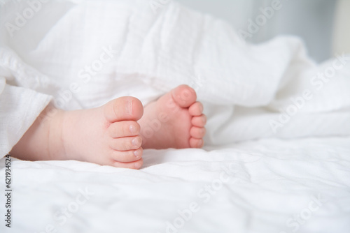 baby bare feet on a white bed with a white blanket