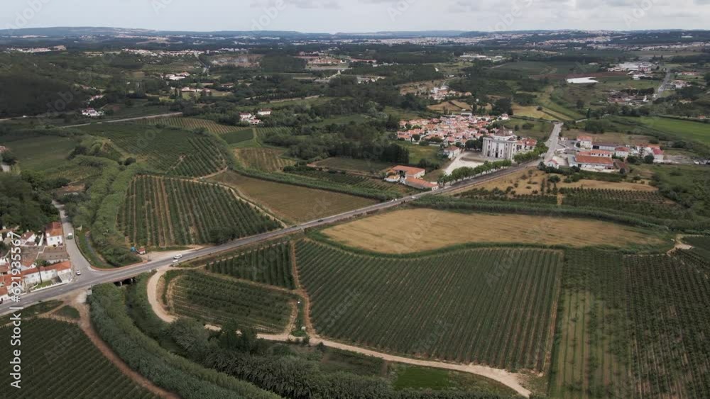 Aerial view of a vehicle driving on the road among agricultural fields in Obidos countryside, Leiria district, Portugal. Aerial view of a vehicle driving on the road among agricultural fields in Obidos countryside, Leiria district, Portugal.