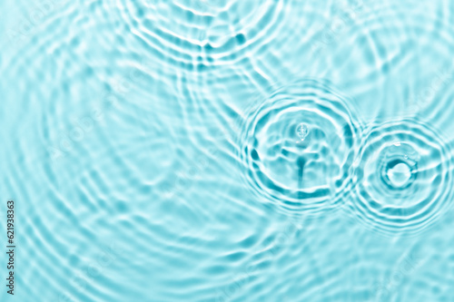 Defocus blurred blue color water ripple surface clear calm texture background with splashing bubbles water drop. Abstract and nature concept. Shiny water wave sunlight reflection shining copy space.