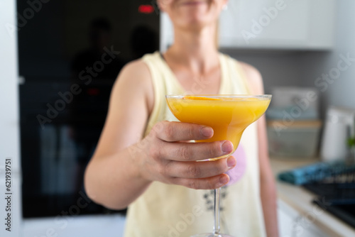 Woman holding an orange cocktail drink in a margarita glass. photo