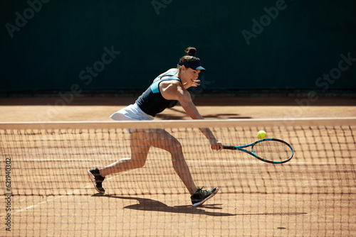 Dynamic image of young woman, professional tennis player in motion during game, hitting ball with racket. Open air training. Concept of sport, hobby, active lifestyle, health, endurance and strength