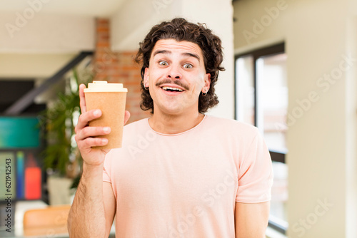 young handsome man holding a hot coffee drink at home interior