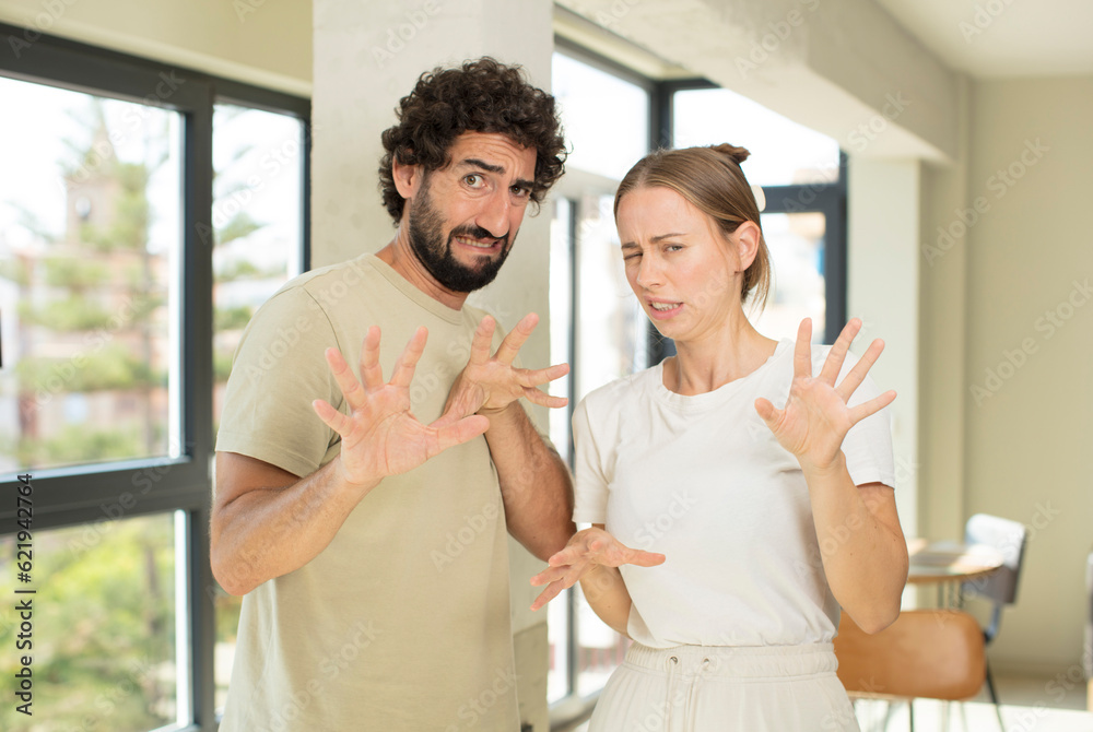 Fototapeta premium young adult couple feeling disgusted and irritated, sticking tongue out, disliking something nasty and yucky