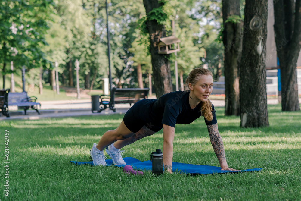portrait of a young satisfied sports girl doing push-ups outdoors while exercising in the park healthy lifestyle concept