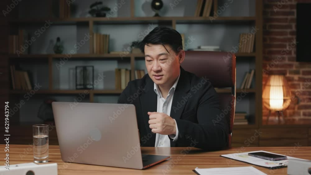Good-looking asian worker in formal wear taking part in online briefing on portable laptop in spacious office. Young man gesturing hands while explaining details of new business project. Good-looking asian worker in formal wear taking part in online briefing on portable laptop in spacious office. Young man gesturing hands while explaining details of new business project.
