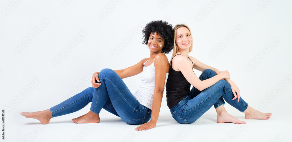 two young girls smiling sitting on the floor with creams on their faces on white background two young girls smiling sitting on the floor with creams on their faces on white background