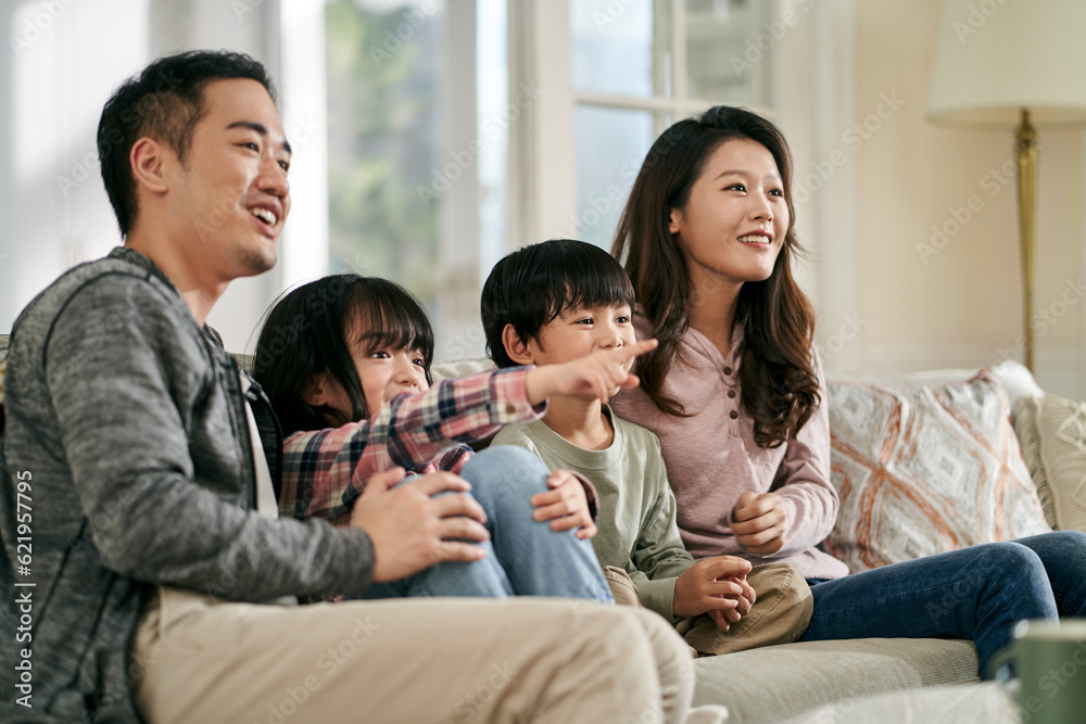 young asian family with two children watching tv together at home young asian family with two children watching tv together at home